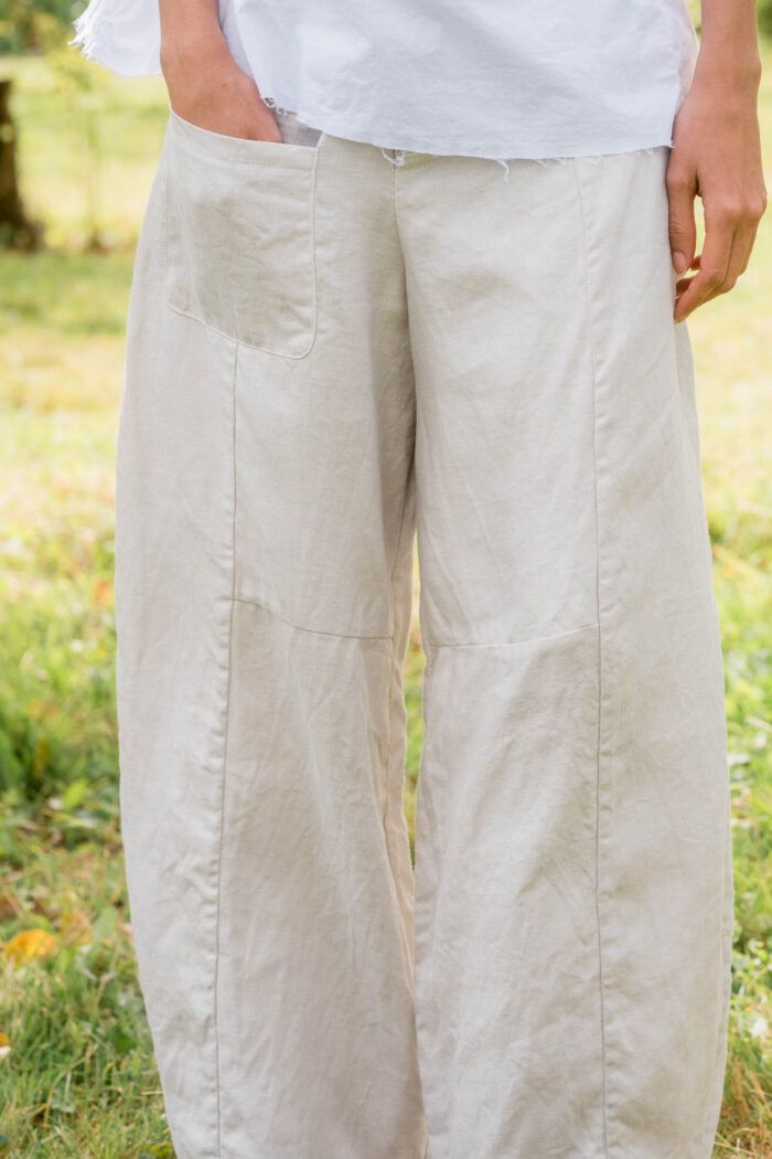 model wearing tailored line pants sula linen barrel leg trousers and apron blouse