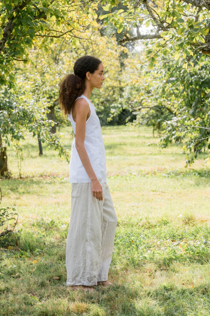 model wearing tailored line pants sula linen barrel leg trousers and apron blouse